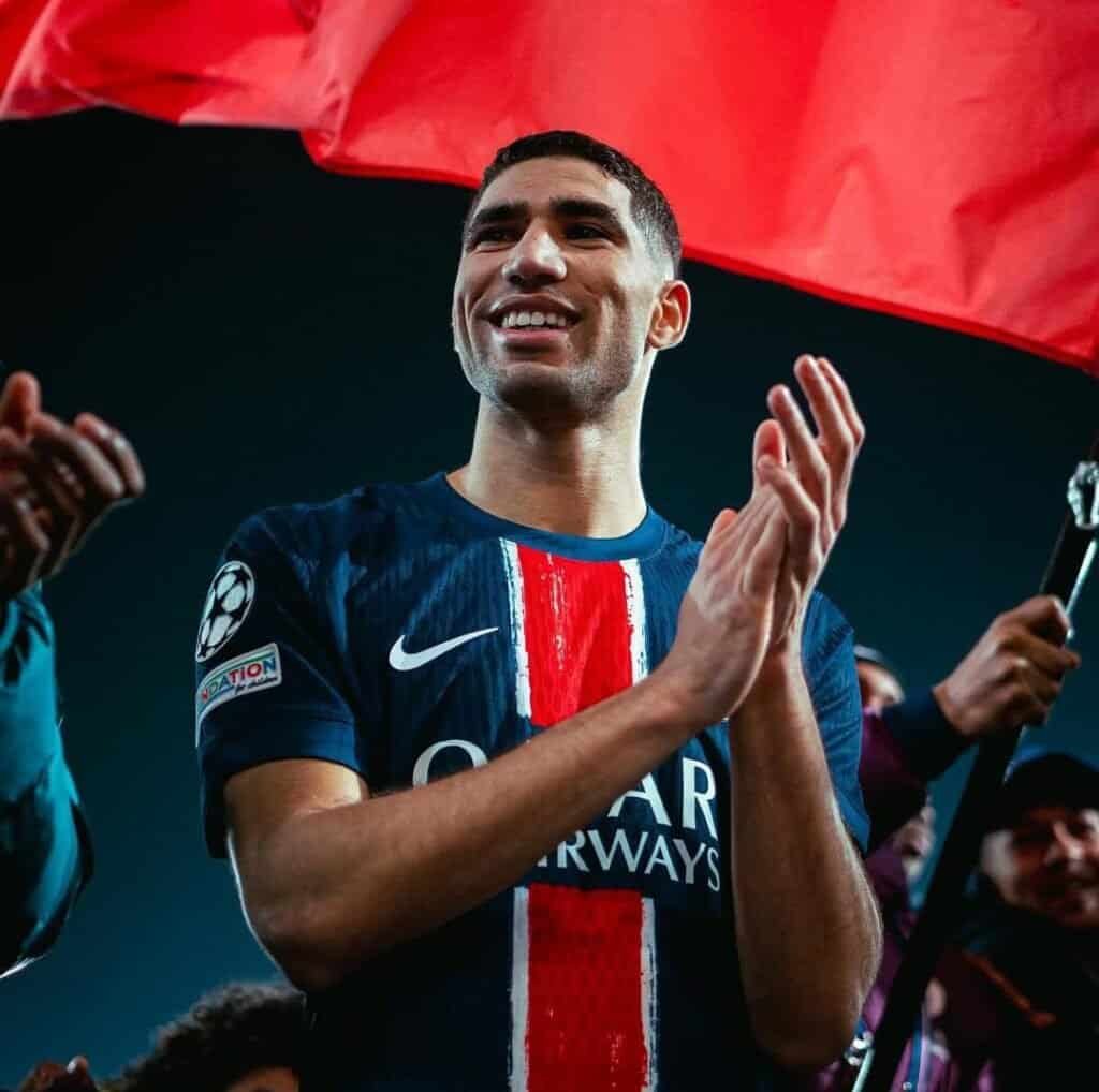 Young male soccer player celebrating victory, wearing Paris Saint-Germain jersey, cheering with fans.