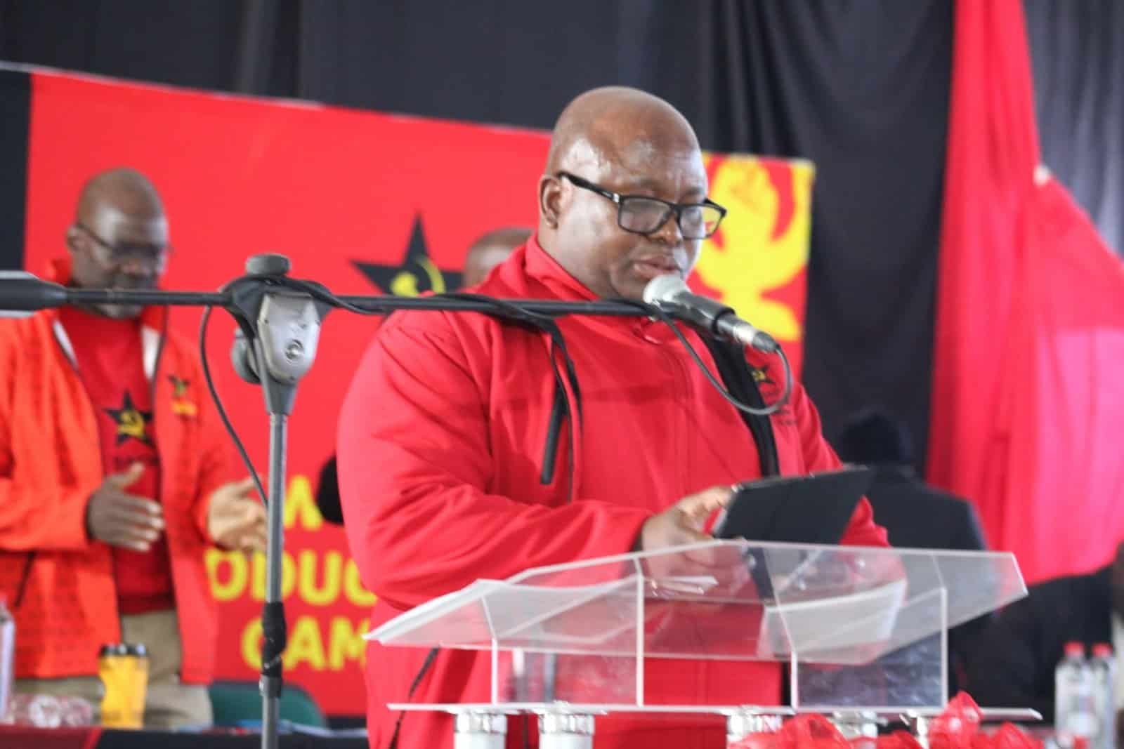 Provincial Secretary Chuene Malebana speaking at a political event in South Africa, wearing red vest with SACP logo.