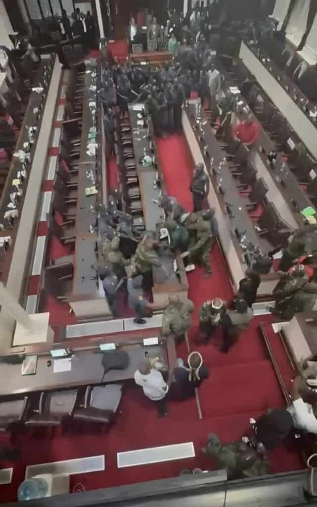 Protest near lawmakers in African legislative hall, showing civil unrest.