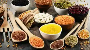 Colorful assortment of spices, legumes, and grains in bowls and spoons.