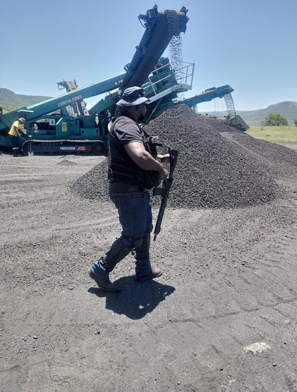 Construction worker inspecting gravel at a mining site.