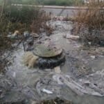 Urban water pollution with trash and debris in a neglected area.