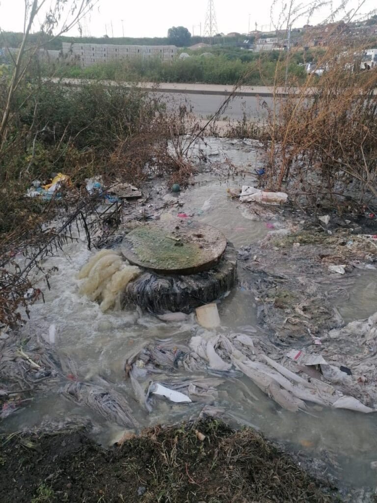 Urban water pollution with trash and debris in a neglected area.