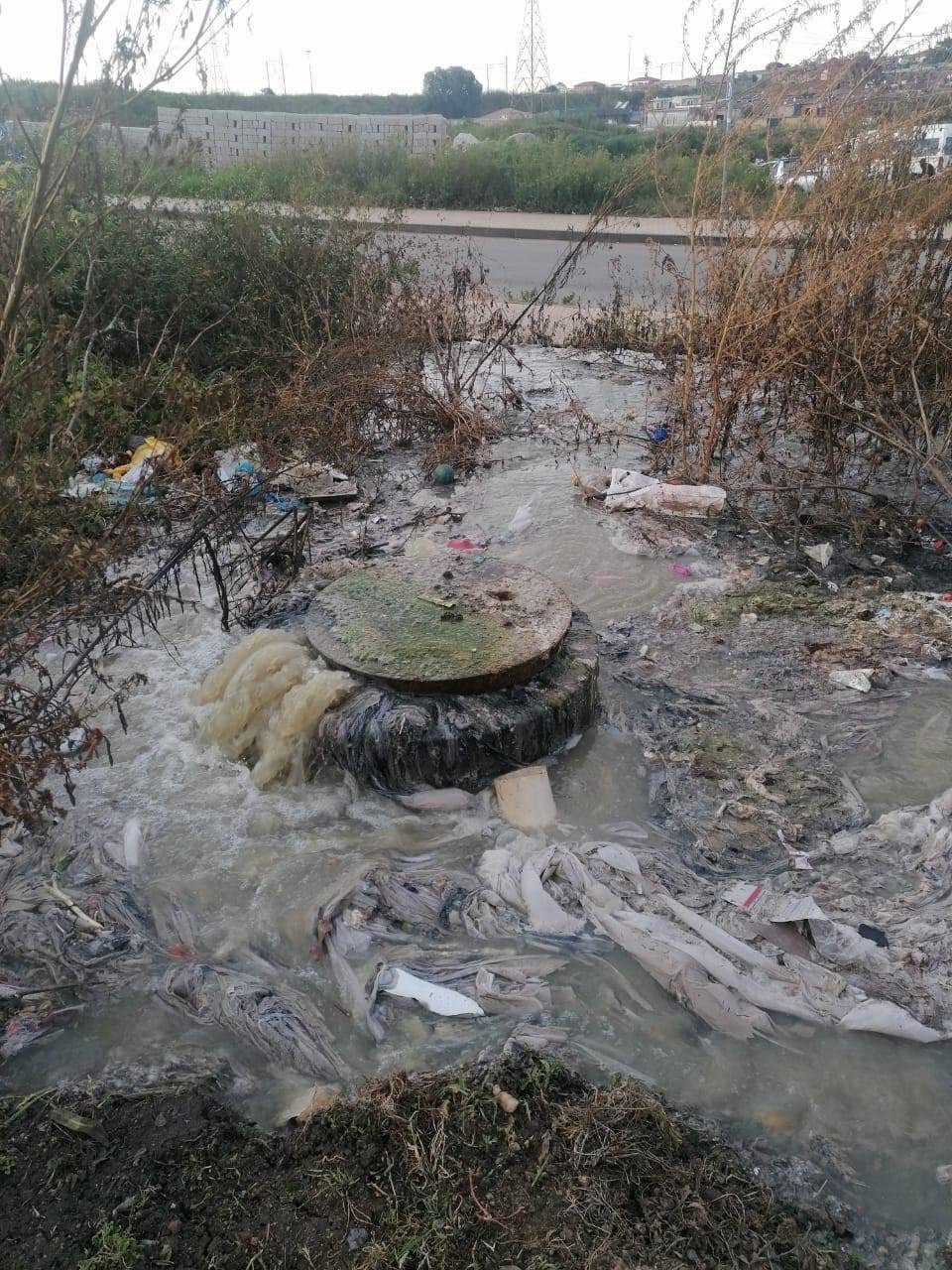 Urban water pollution with trash and debris in a neglected area.