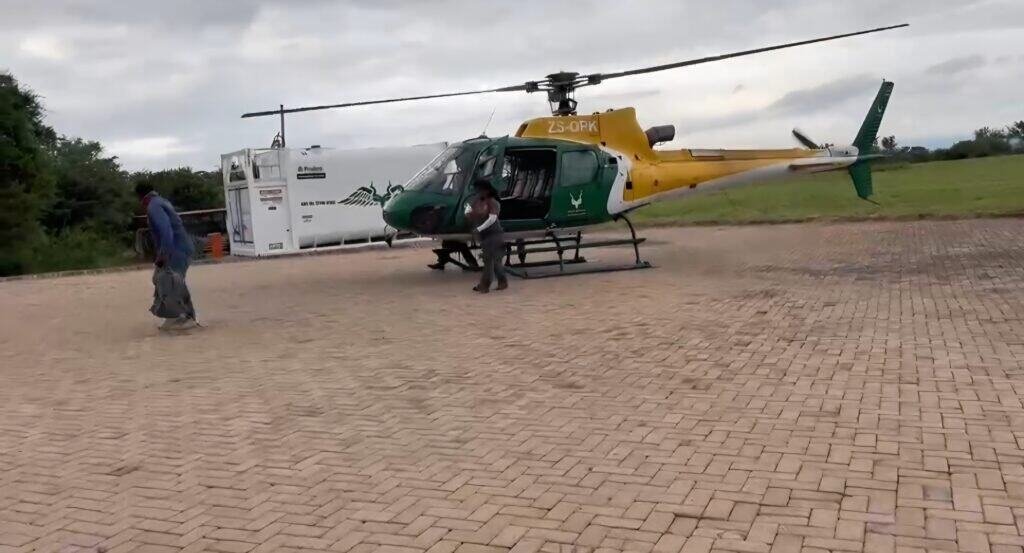Helicopter parked on the tarmac with personnel nearby.