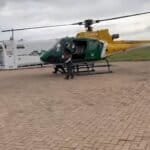 Helicopter parked on the tarmac with personnel nearby.