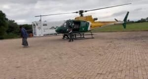 Helicopter parked on the tarmac with personnel nearby.