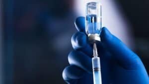 Egypt Aims to Produce 140 Million Vaccine Doses Annually by 2030. Healthcare professional administering COVID-19 vaccine with syringe.