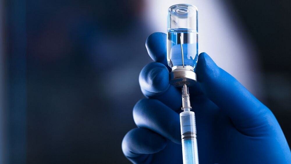 Egypt Aims to Produce 140 Million Vaccine Doses Annually by 2030. Healthcare professional administering COVID-19 vaccine with syringe.