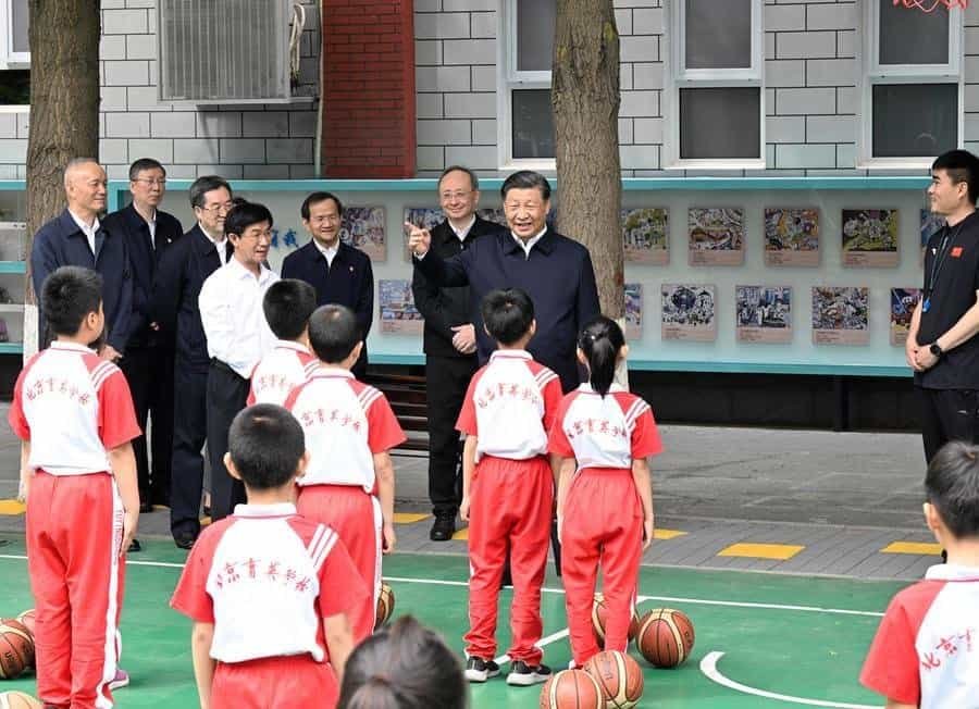 Chinese President Xi Jinping, also general secretary of the Communist Party of China Central Committee and chairman of the Central Military Commission, talks with students on the basketball court of Beijing Yuying School in Beijing