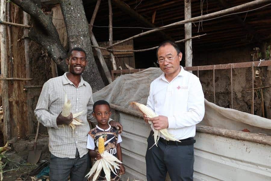 Abu Negash (L), with a newly-harvested ear of corn, poses for a photo with his son and a Chinese agricultural expert at Godino Jitu Village in Oromia Region, Ethiopia, on Nov. 26, 2025. (Xinhua/Liu Fangqiang)