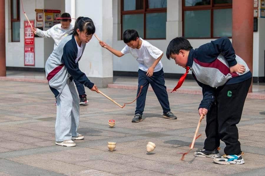 Students play spinning tops during a break at a primary school in Jinhua, east China's Zhejiang Province, March 25, 2024. (Photo by Hu Xiaofei/Xinhua)