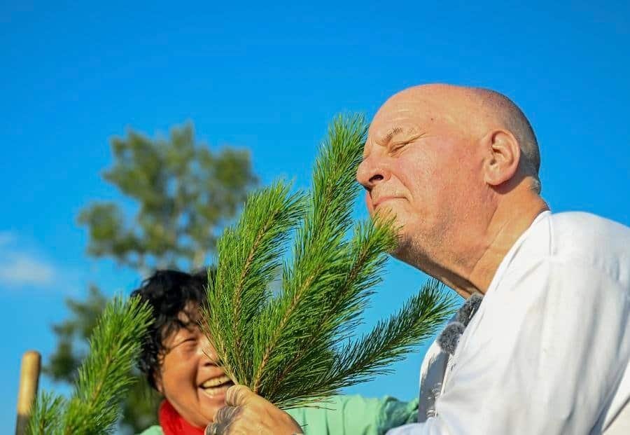 Ronald Sakolsky (R) sniffs a sapling after planting it with Yin Yuzhen in the Maowusu Sandy Land in north China's Inner Mongolia Autonomous Region, Aug. 24, 2026. (Xinhua/Lian Zhen)